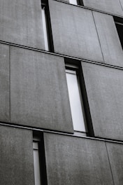 Workers assembling large precast concrete panels on a building framework outdoors.