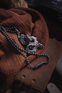 A Viking-inspired bracelet with hammered metal and earthy jasper stones, laid atop a leather-bound journal.