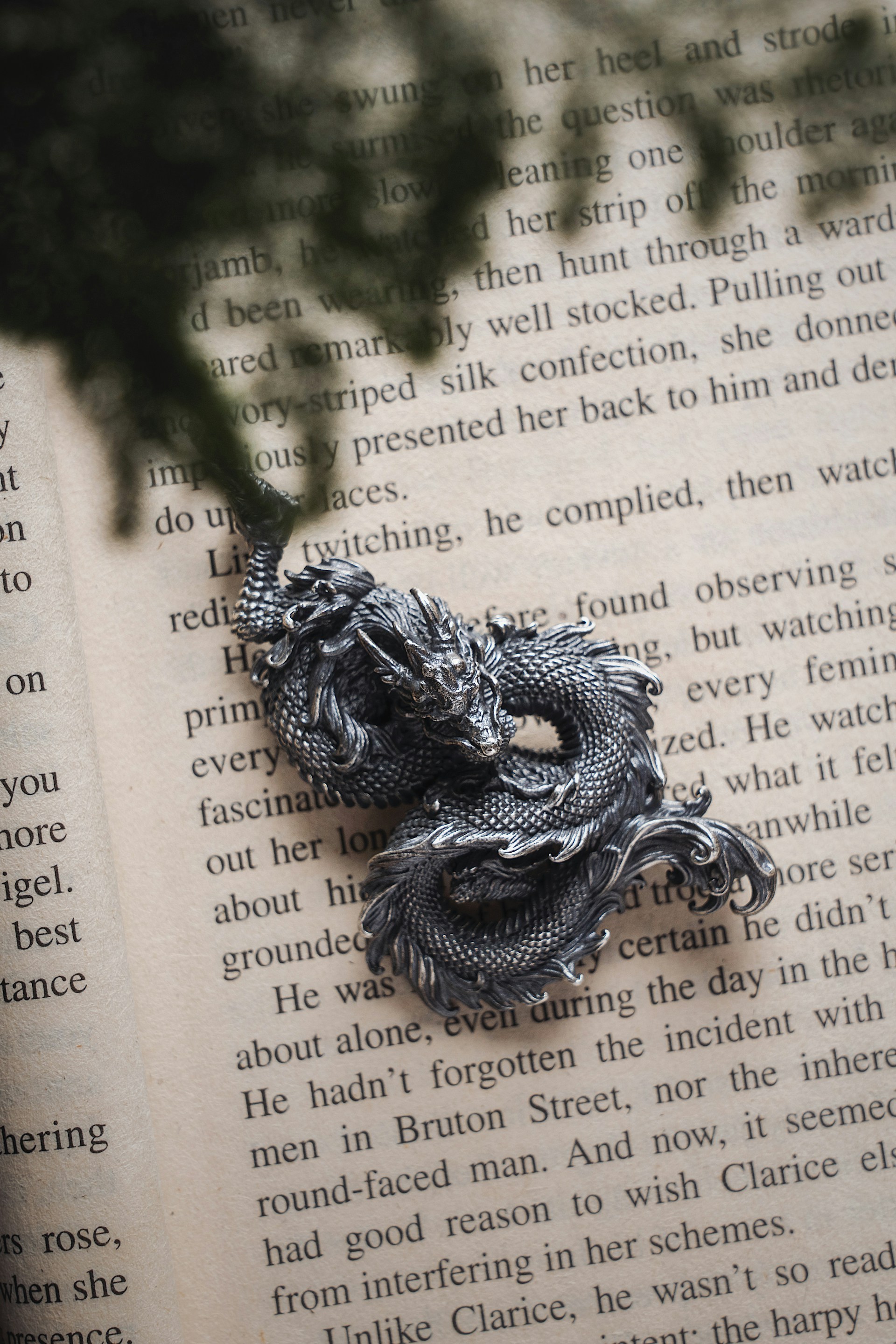 An intricate dragon sculpture curling protectively around an ancient, weathered book.