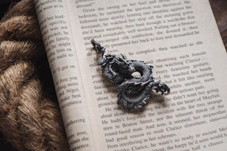 An ancient leather-bound book opened to a page with a detailed dragon sketch.