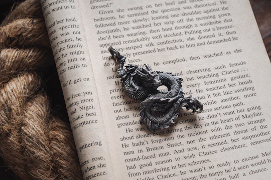 An ancient leather-bound book opened to a page with a detailed dragon sketch.