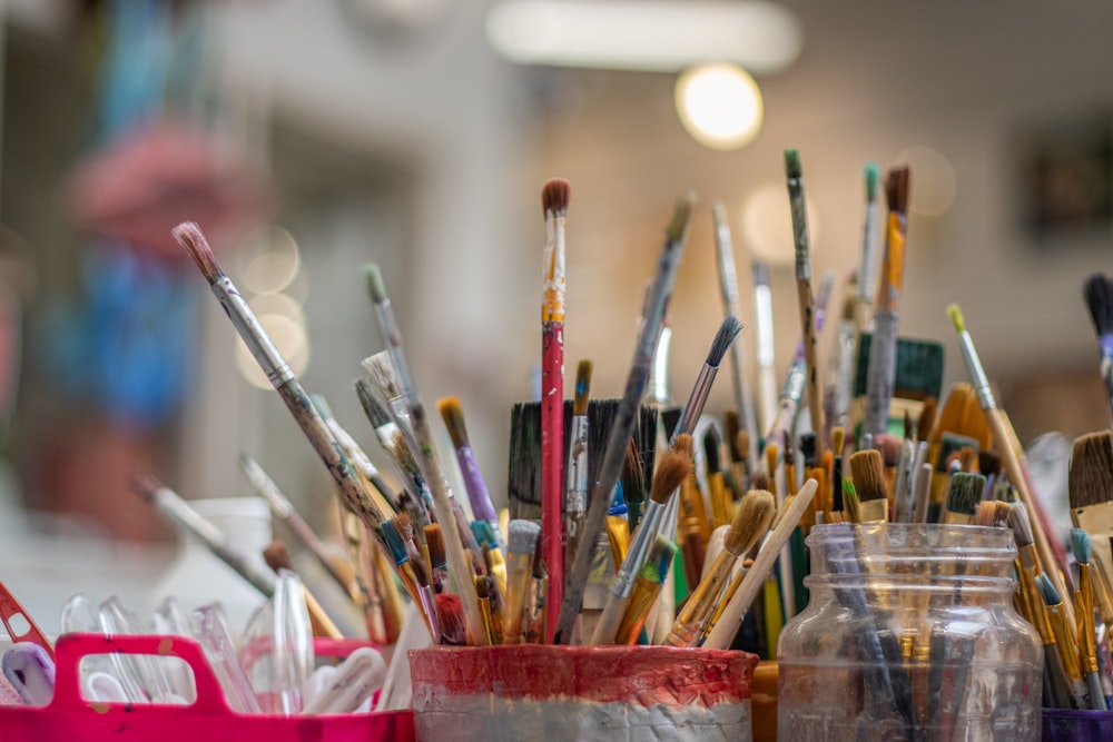 a close up of a cup full of paint brushes