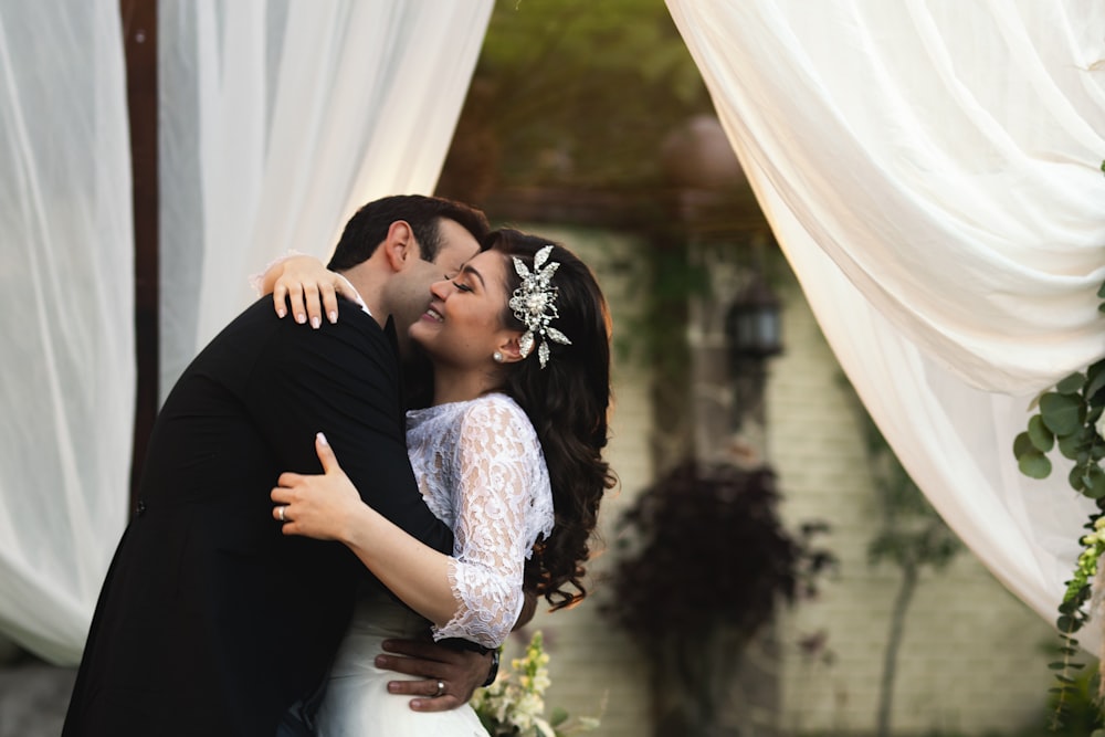 a bride and groom embracing each other in front of a wedding arch