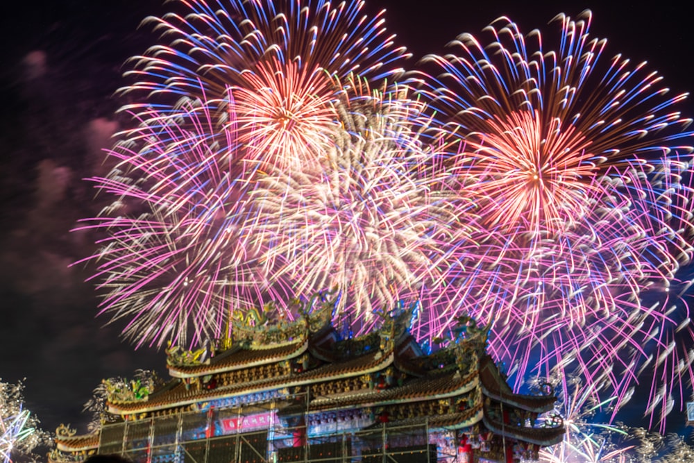 fireworks are lit up in the sky above a building