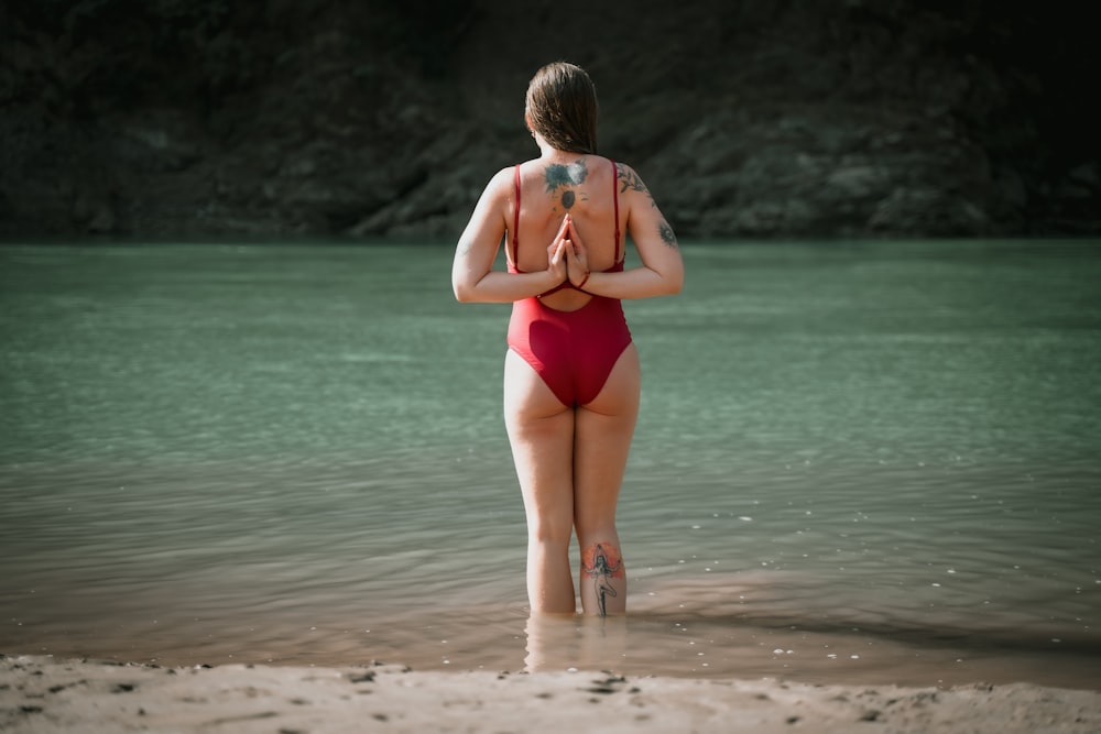 a woman in a red swimsuit standing in the water
