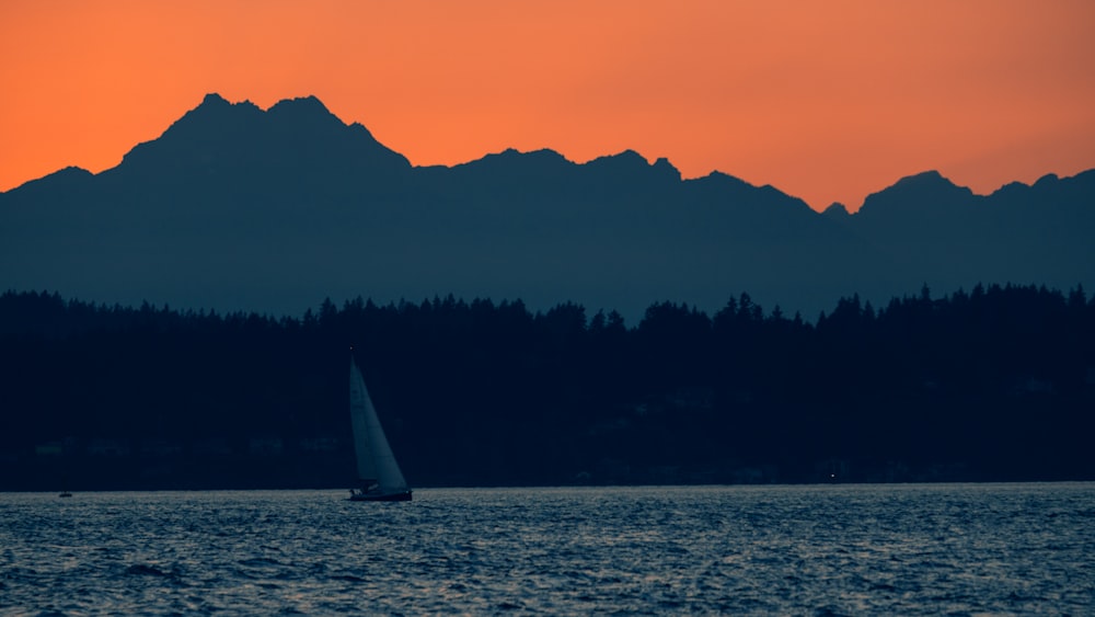 a sailboat in the water with a mountain in the background