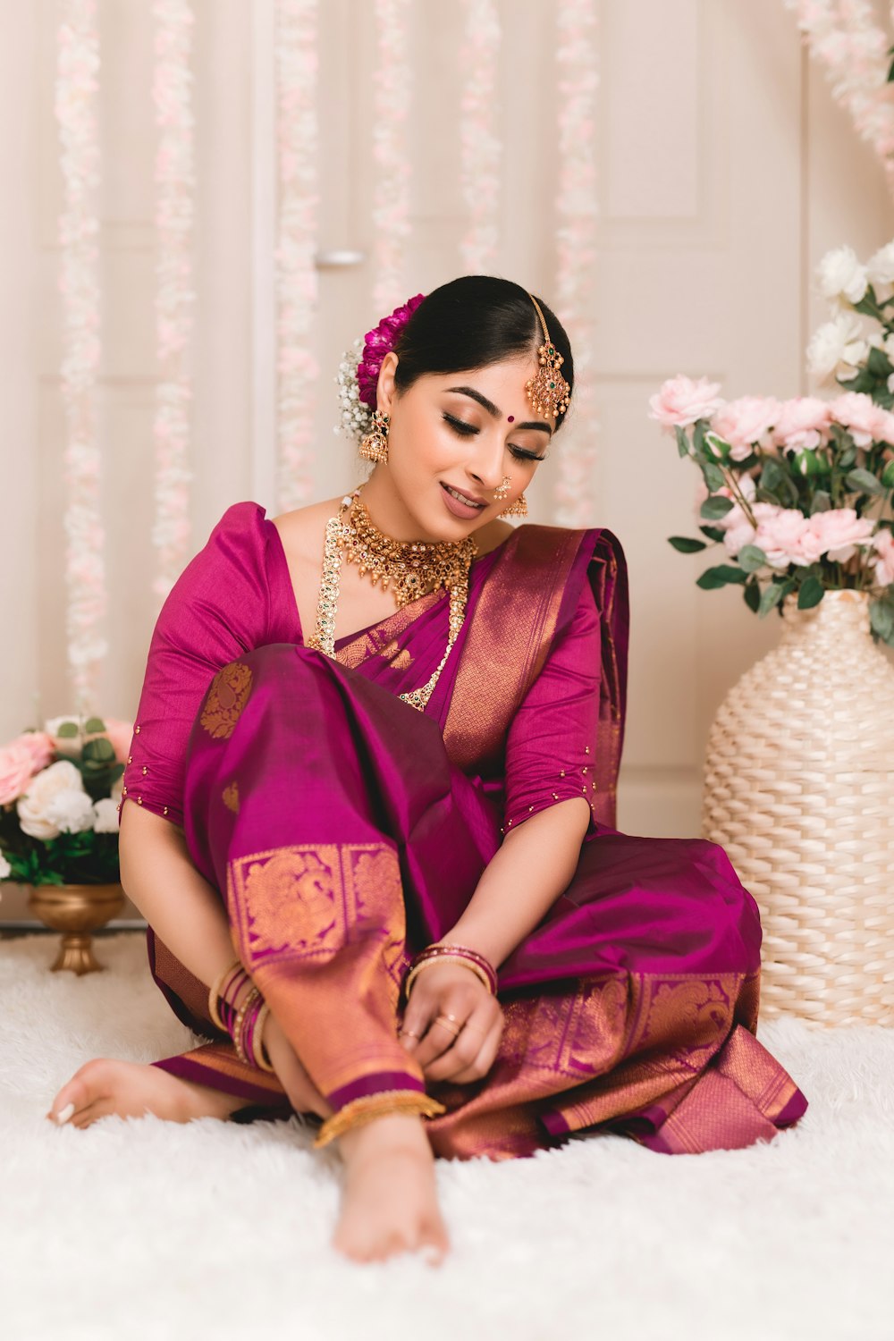 a woman in a pink sari sitting on a white rug