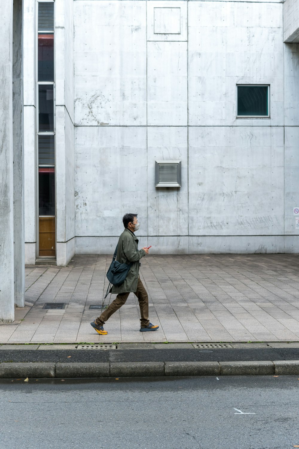 a man walking down a street past a tall building