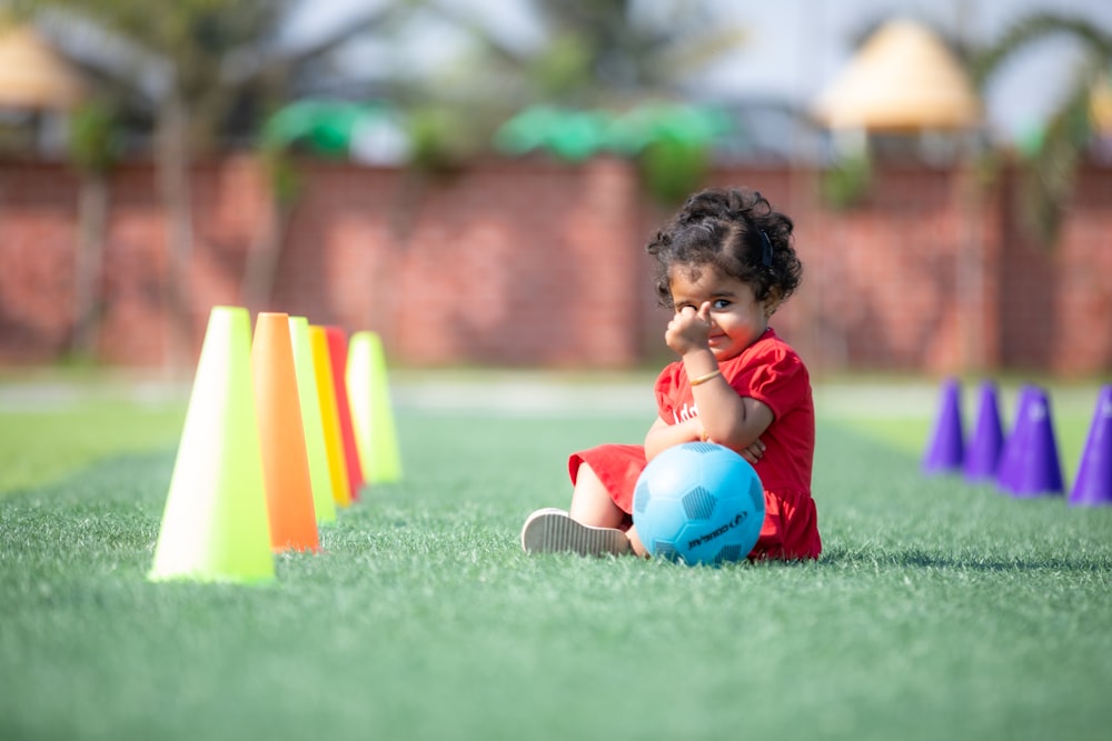 a little girl sitting on the ground next to some cones