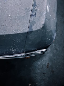 A close-up of a colorful clown nose resting on a dusty car hood.