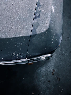 Close-up of a dusty car hood before the wash, showing dirt and grime buildup.