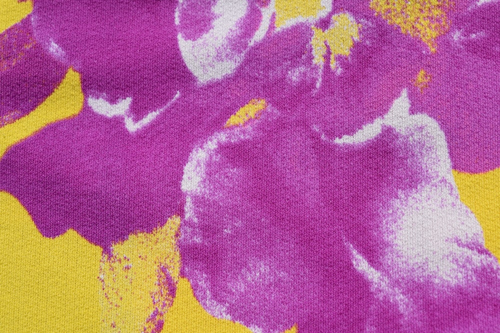 a close up of a purple flower on a yellow background