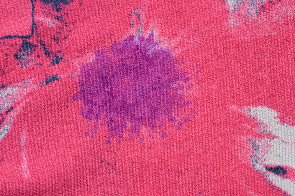 a close up of a pink shirt with a purple flower on it