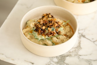 A delicious bowl of baked feta pasta topped with roasted garlic and pine nuts.