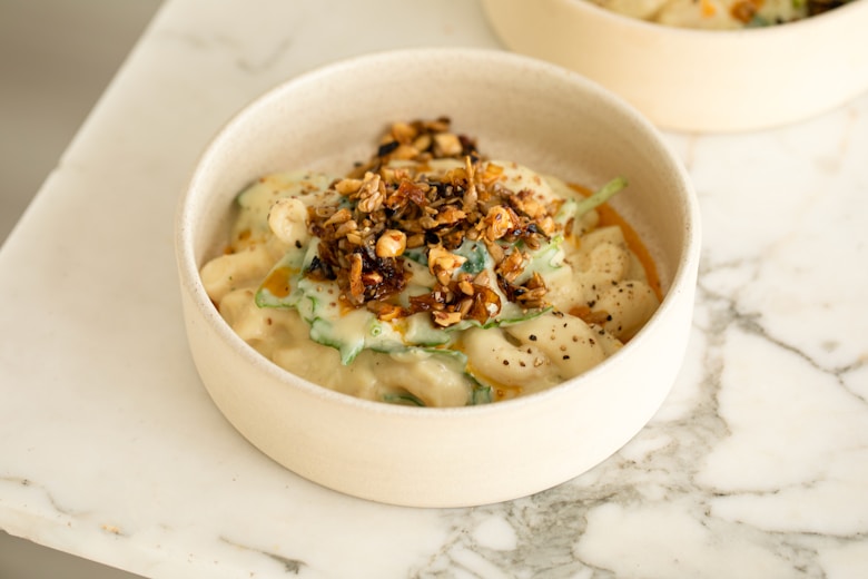 A delicious bowl of baked feta pasta topped with roasted garlic and pine nuts.