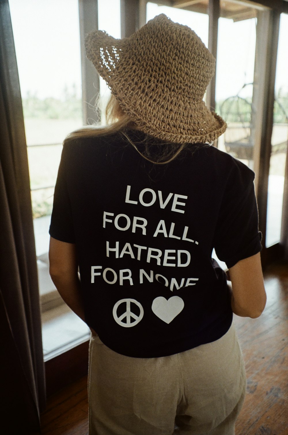 a woman wearing a hat looking out a window