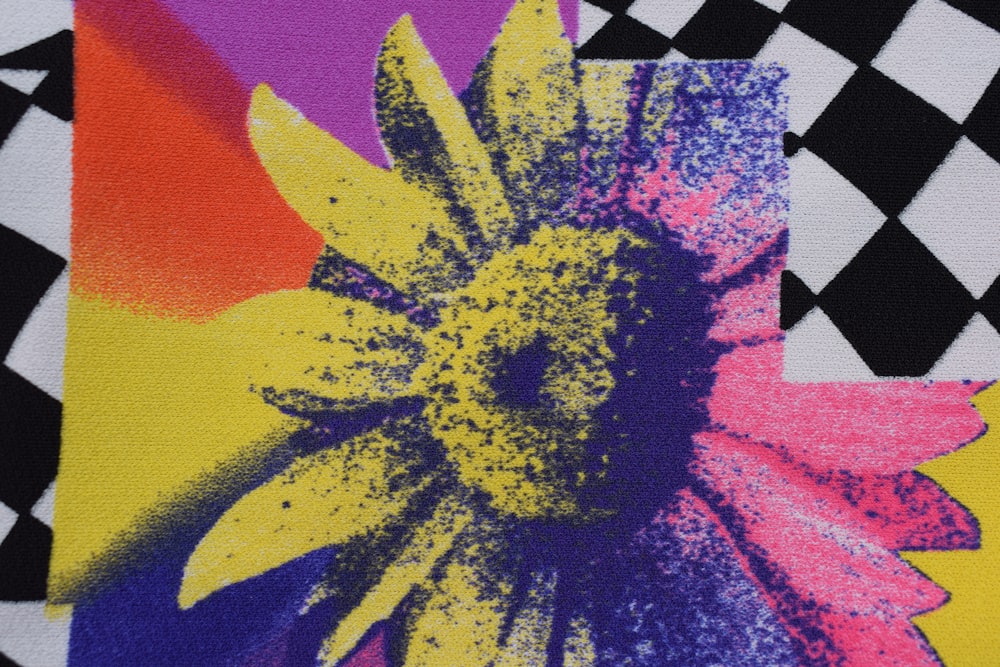 a close up of a colorful flower on a black and white checkered background