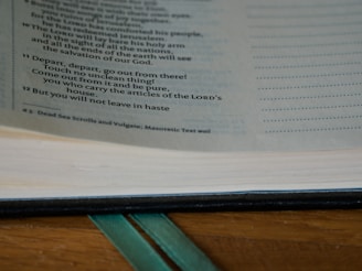 Close-up of a hand turning the yellowed page of a vintage book next to a knitted woolen bookmark.