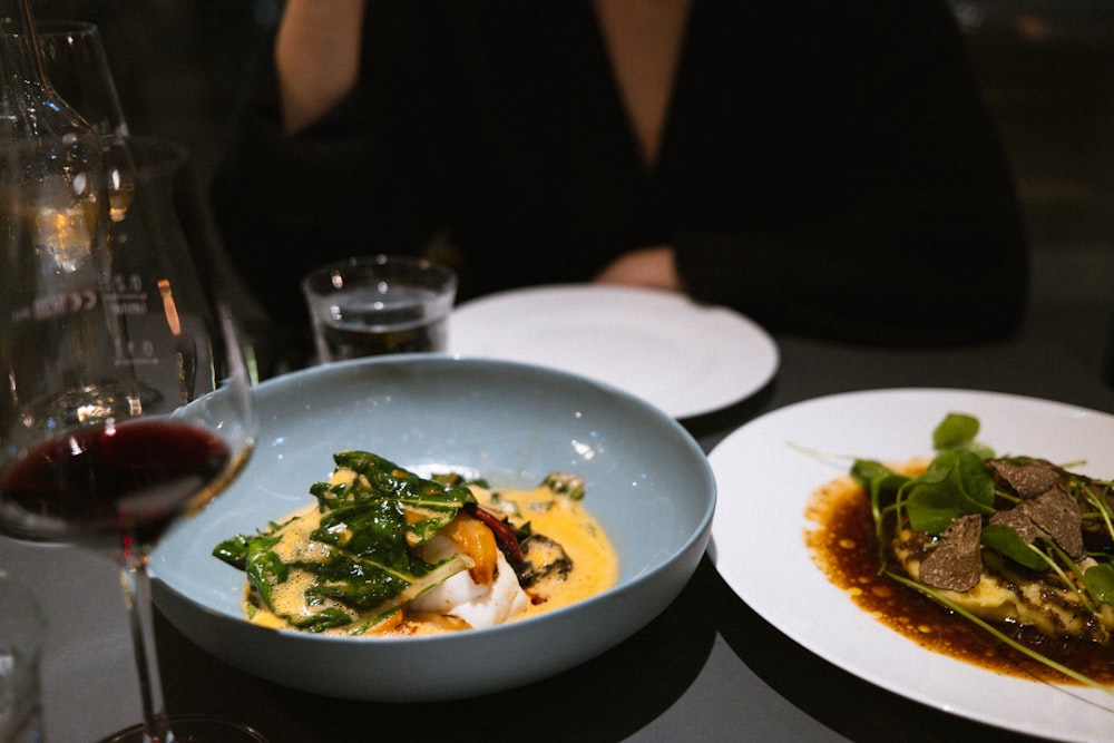 two plates of food and a glass of wine on a table