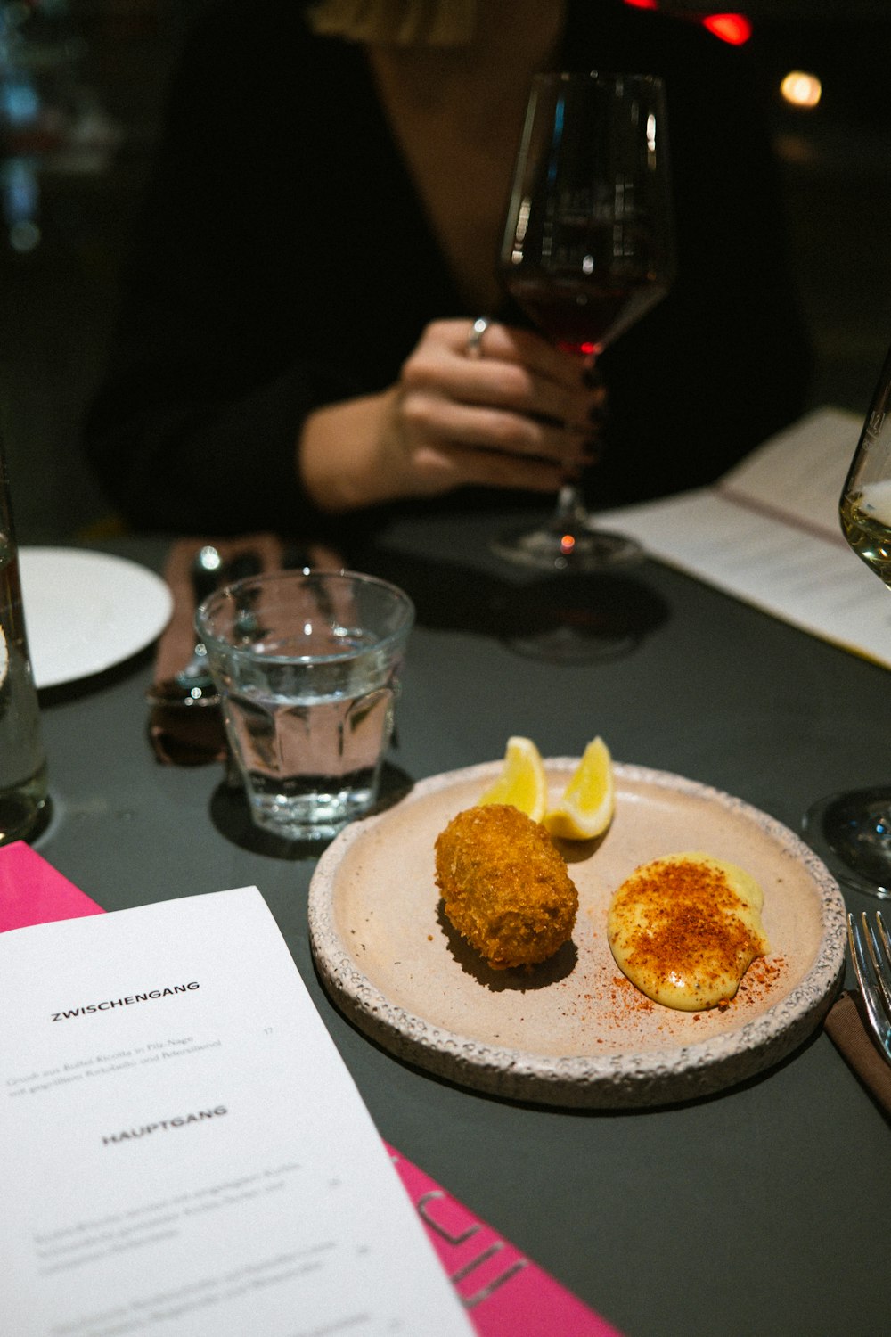 a person sitting at a table with a glass of wine