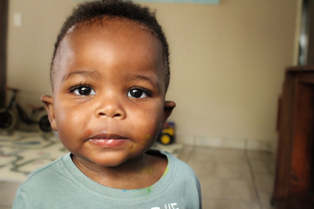 a little boy with a blue shirt on looking at the camera