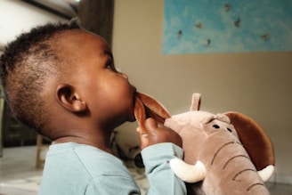 a small child is playing with a stuffed elephant