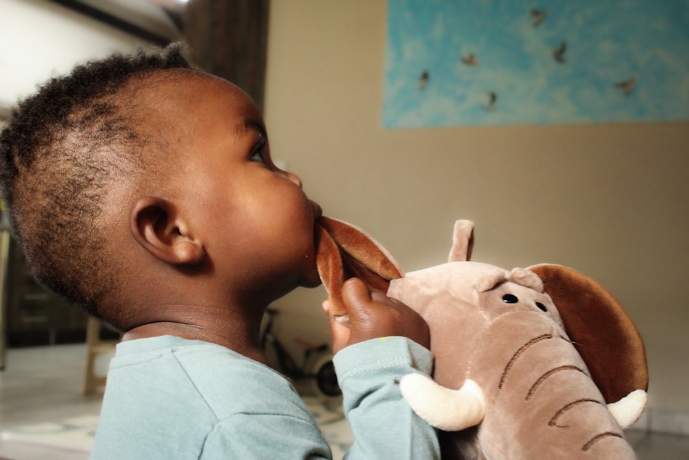 a small child is playing with a stuffed elephant