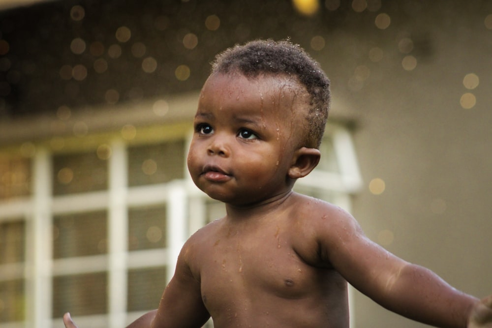 a small child with a shirt on standing in front of a house