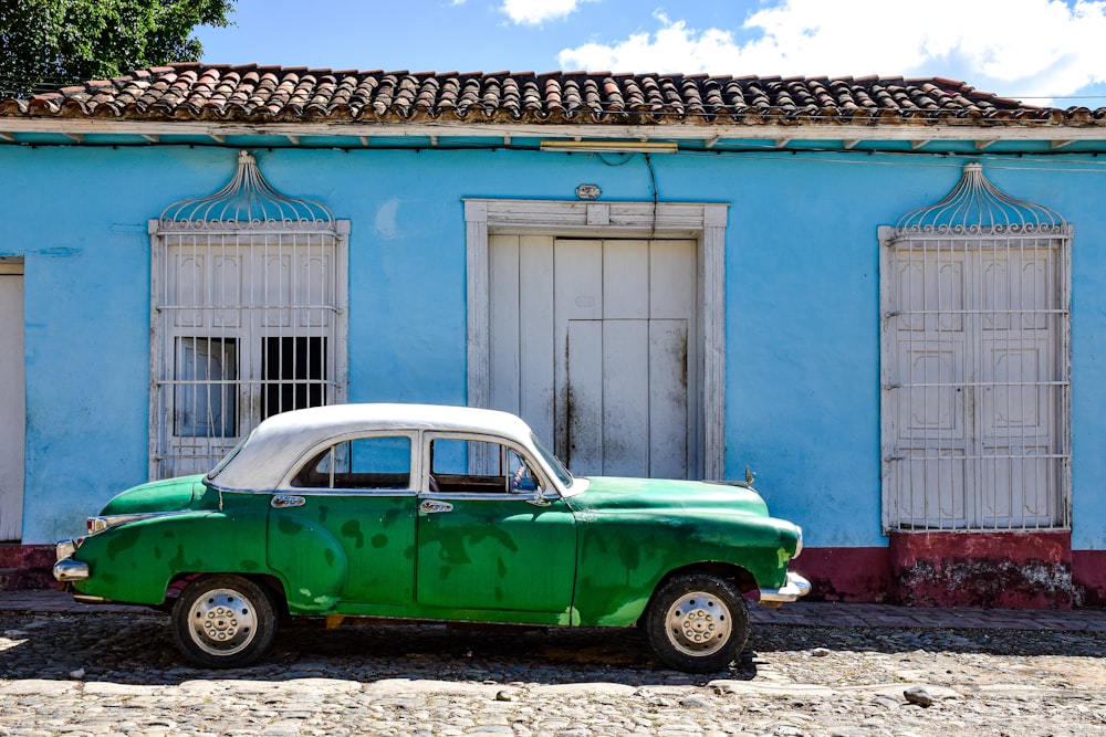 a green car parked in front of a blue building