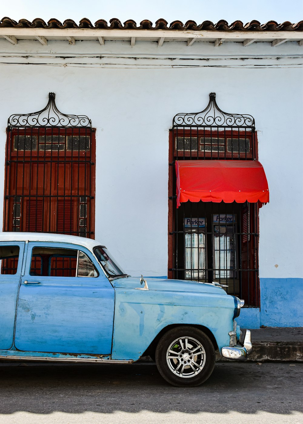 a blue car parked in front of a white building