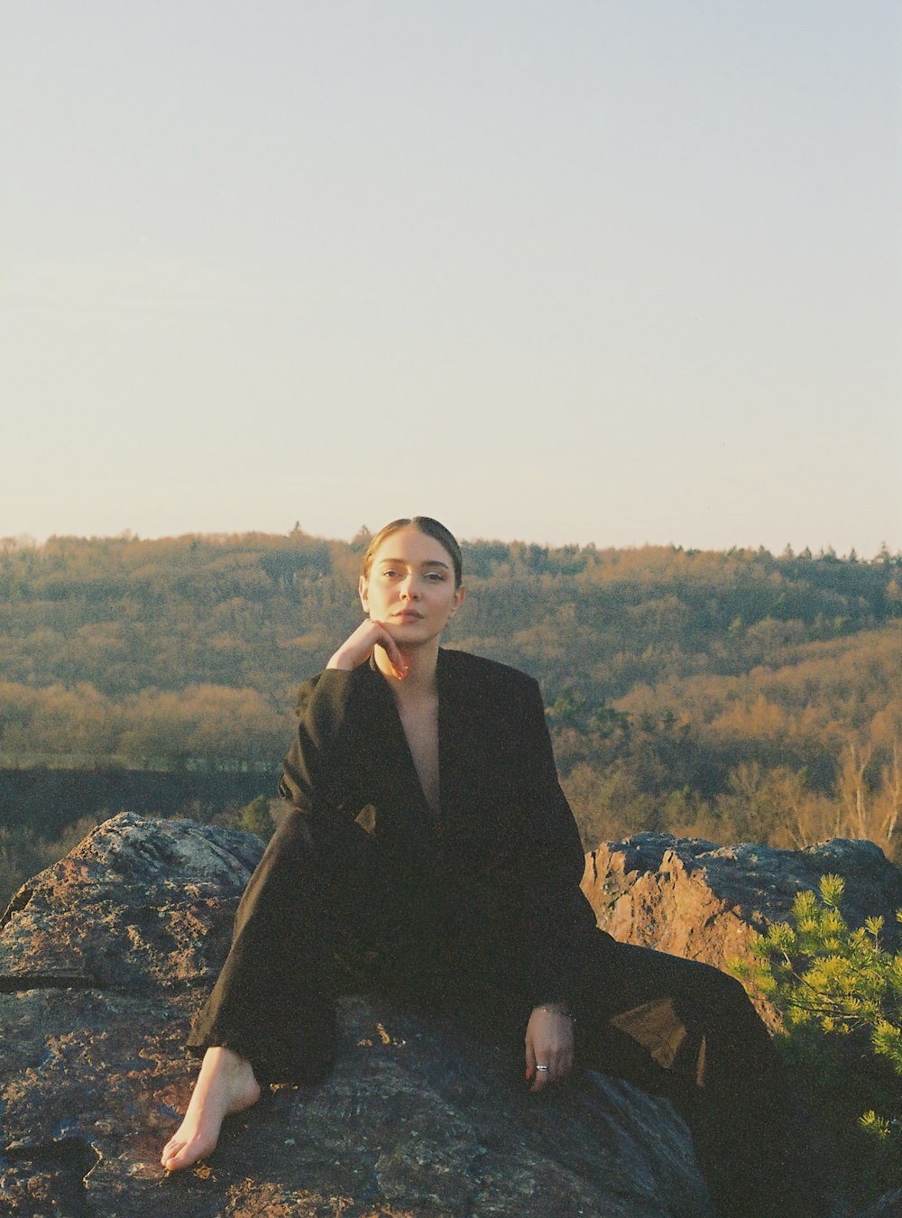 a woman sitting on top of a large rock