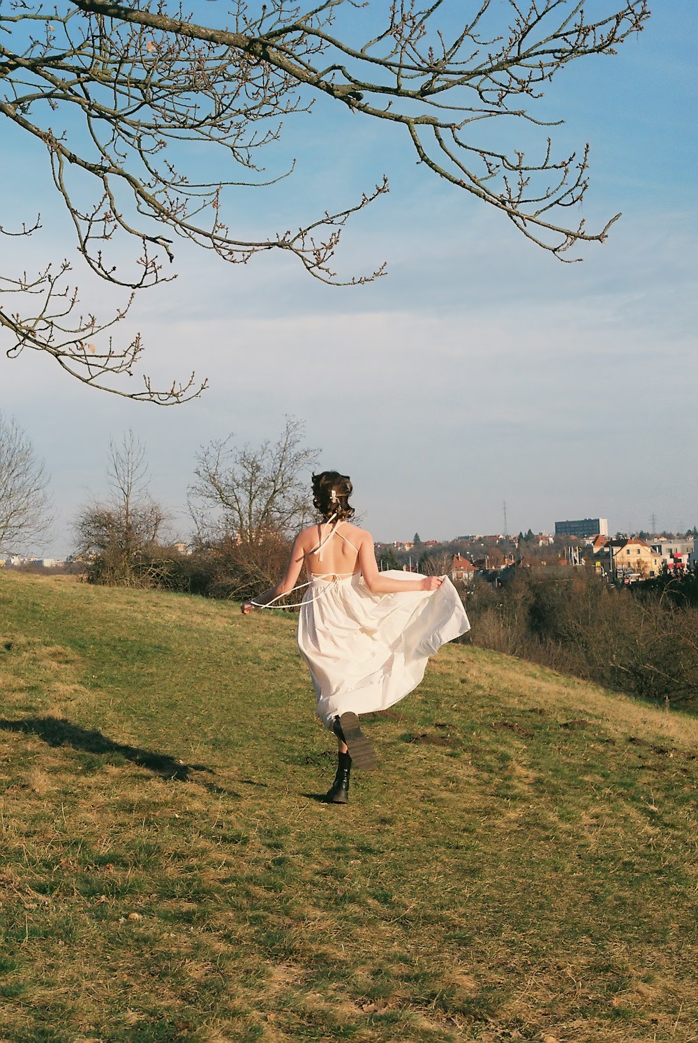 a woman in a white dress walking across a field