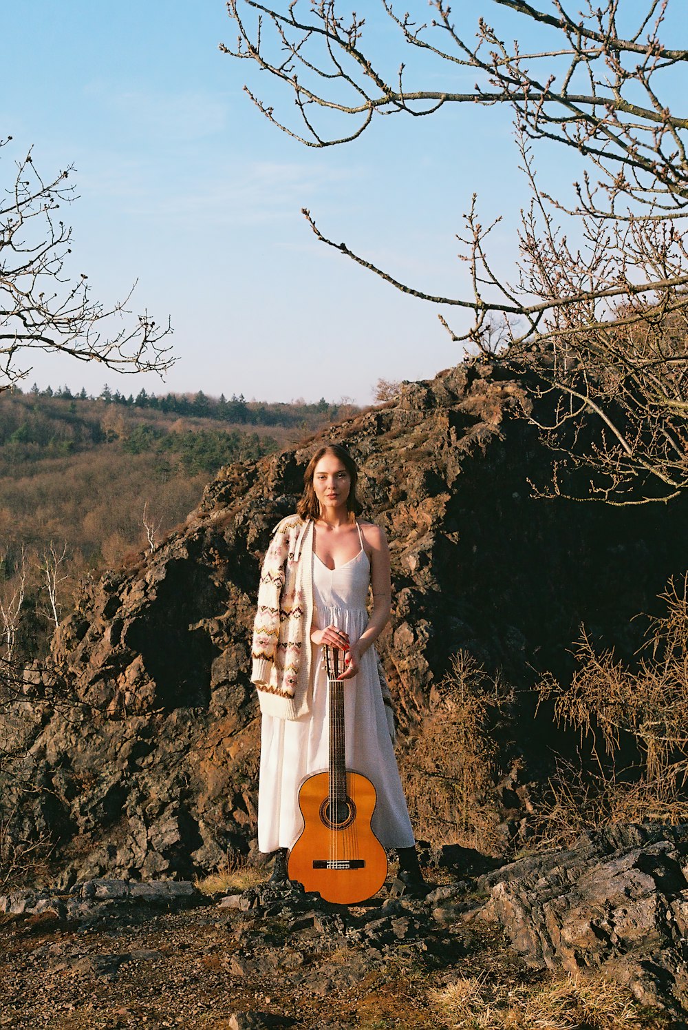 eine Frau in einem weißen Kleid, die eine Gitarre hält