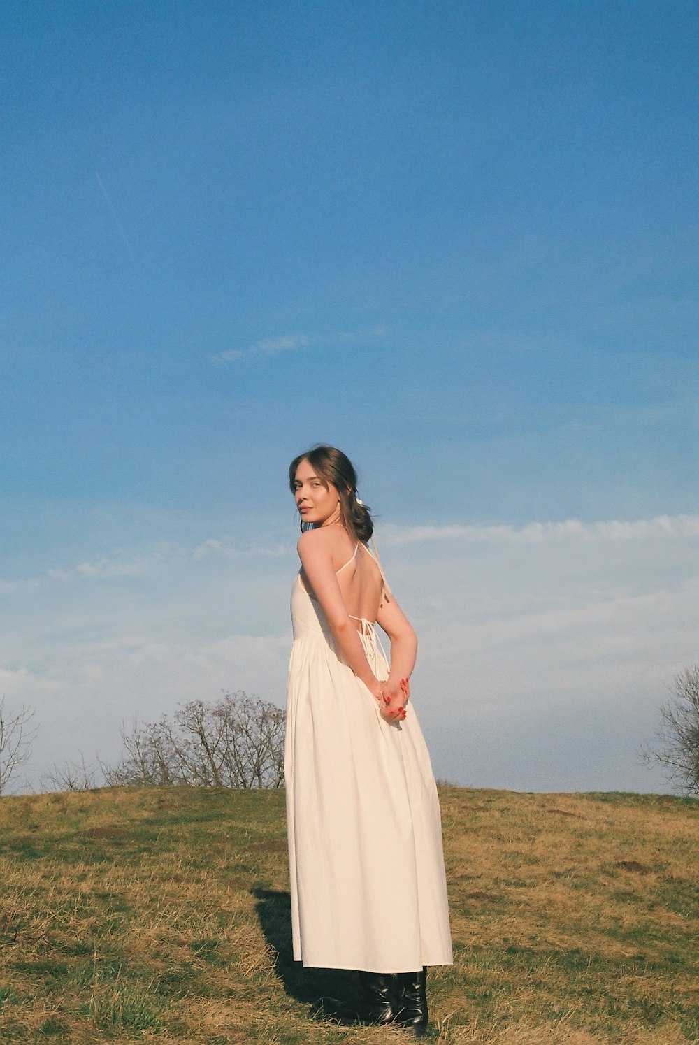 a woman in a white dress standing in a field