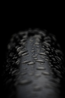 Artistic shot of probiotic cleaning product droplets on a smooth black surface reflecting soft light.