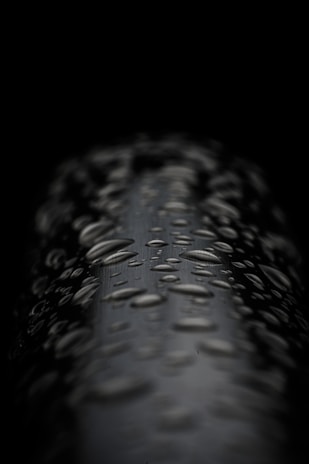 Artistic shot of probiotic cleaning product droplets on a smooth black surface reflecting soft light.