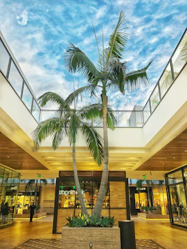 Shopping mall atrium adorned with large artificial trees and decorative pots.