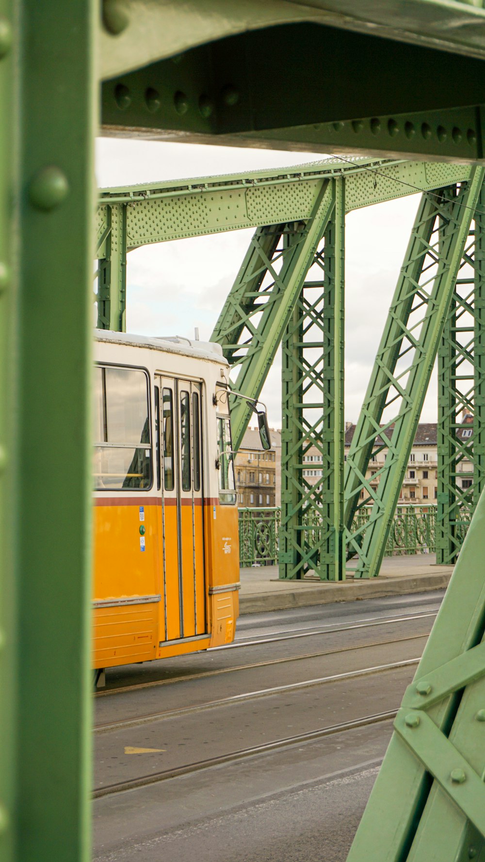 a yellow and white bus driving over a bridge