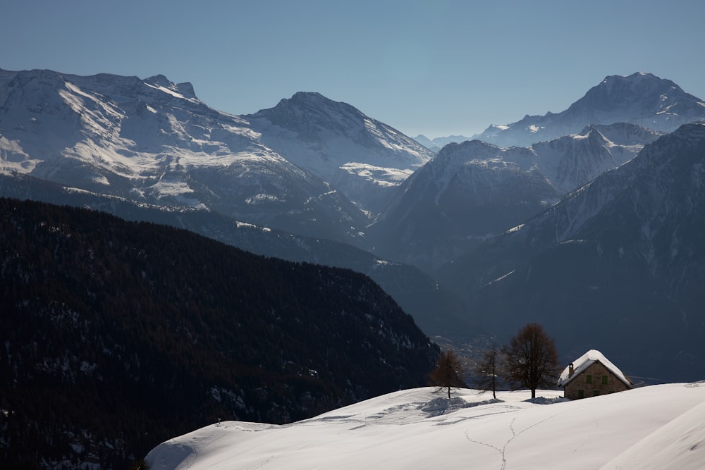 a snow covered mountain range with a house in the foreground