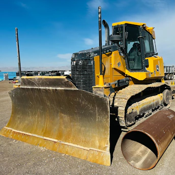 A bulldozer smoothing out a large construction site under a clear blue sky.