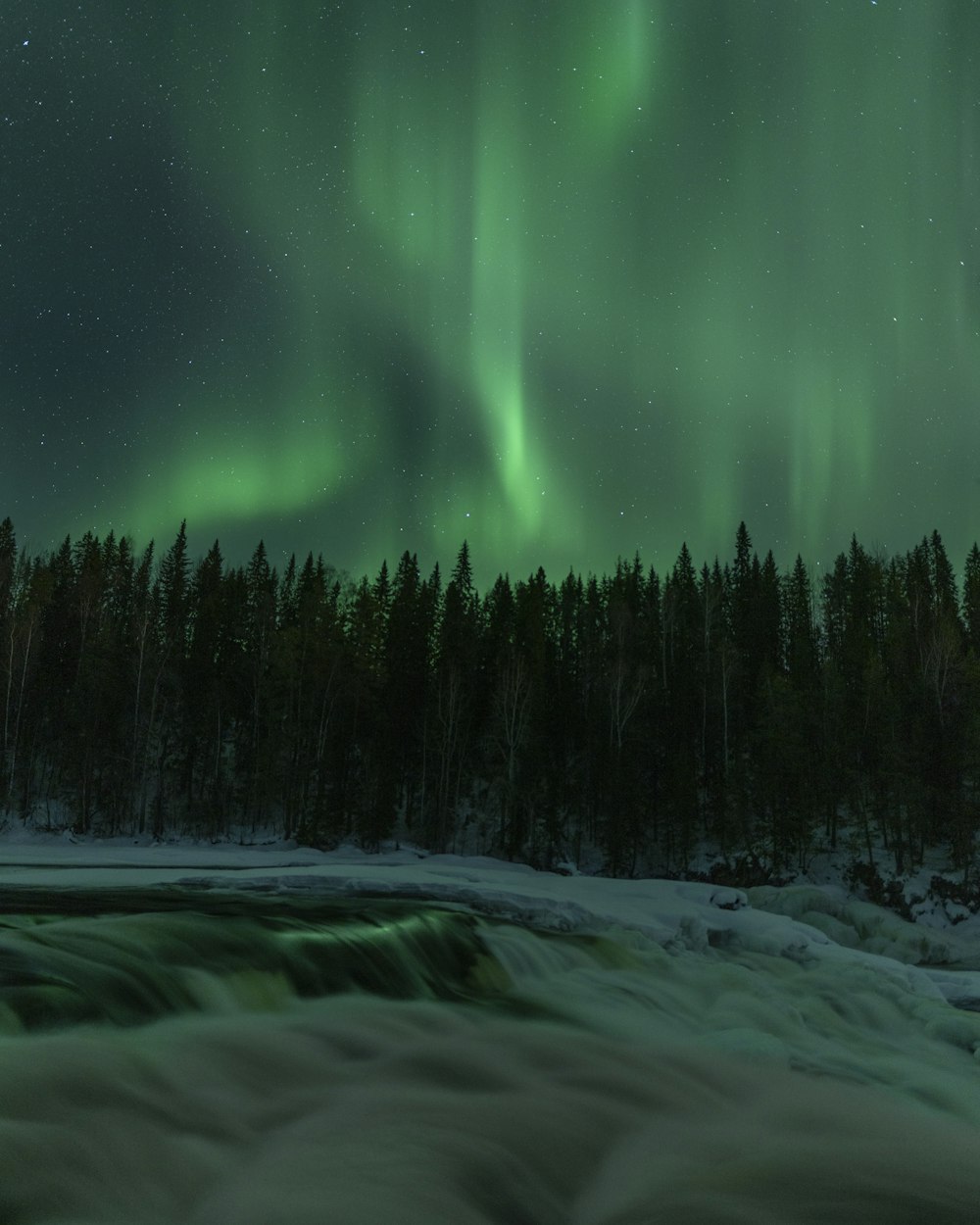 a green and white aurora bore over a river