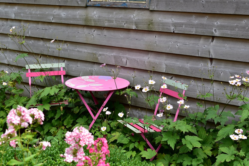 a pink table and two pink chairs in a garden