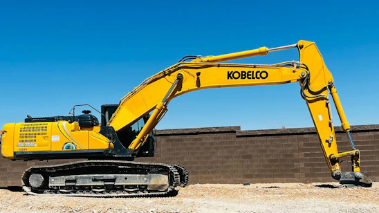 A friendly technician inspecting a yellow construction machine on a sunny worksite.