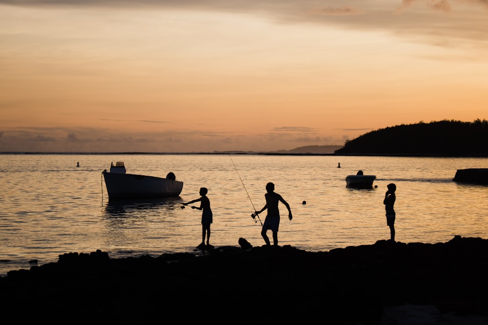 a group of people standing on top of a beach next to a body of water