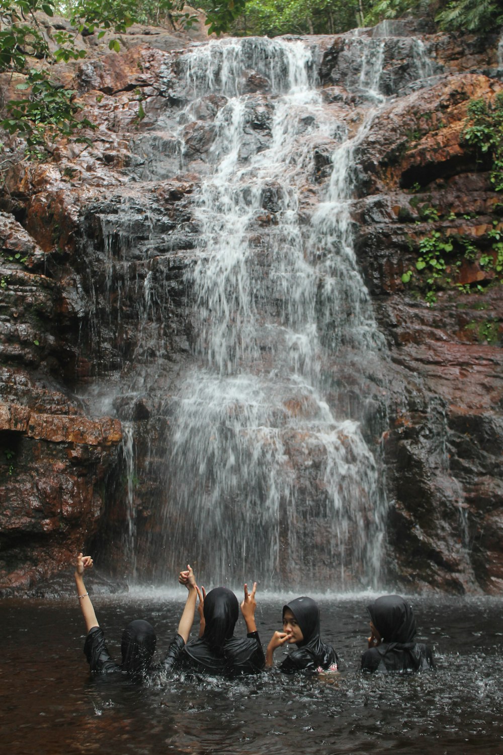 a group of people standing in front of a waterfall