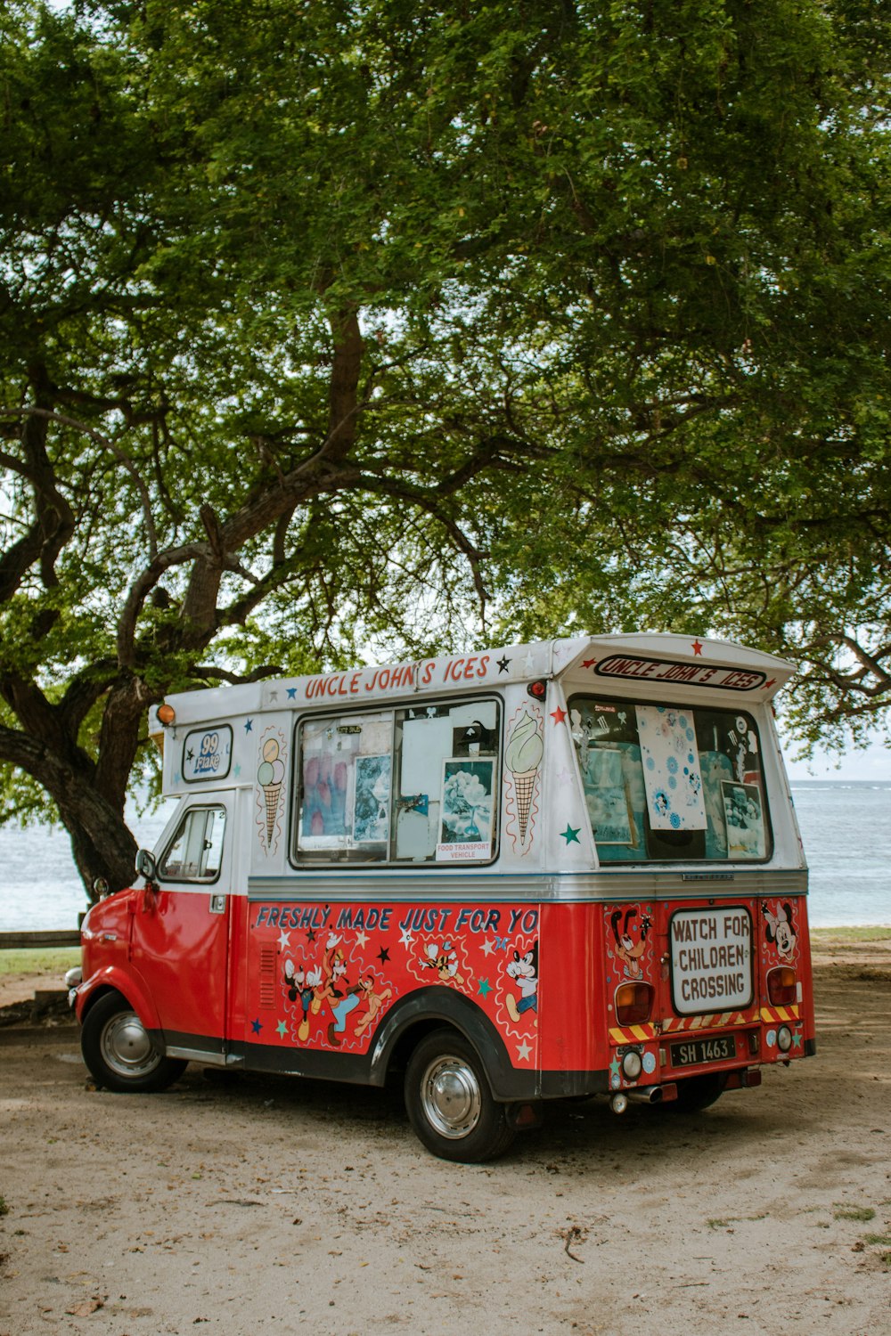 a red and white food truck parked under a tree