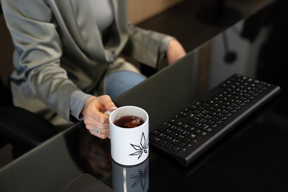 a person sitting at a desk with a cup of coffee