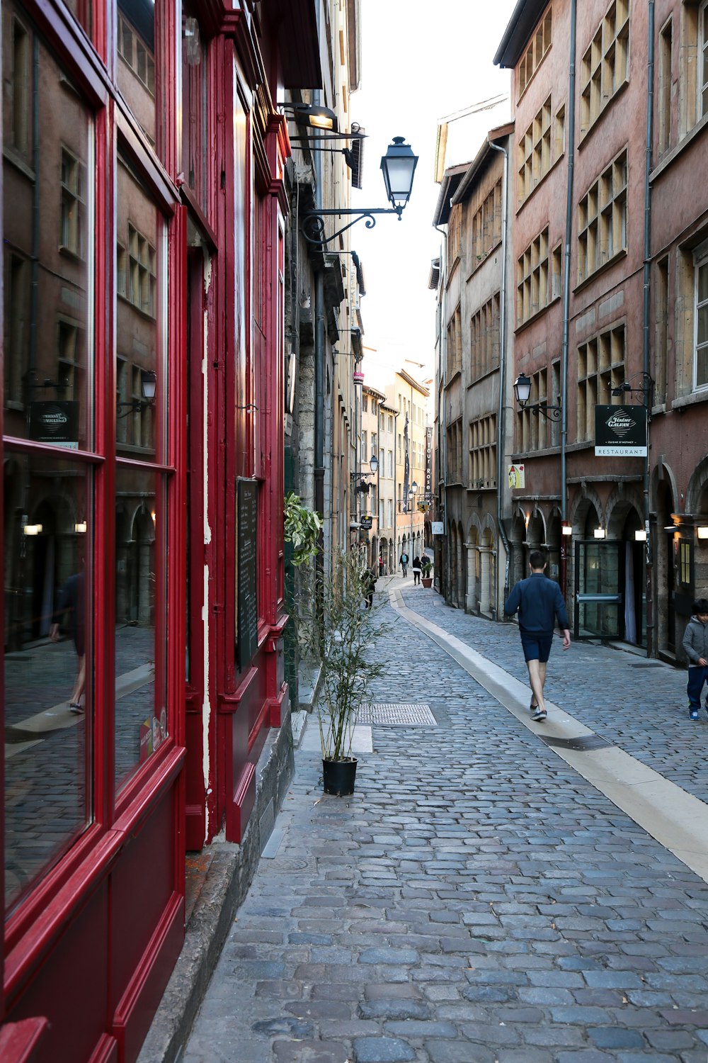 a man walking down a street next to tall buildings