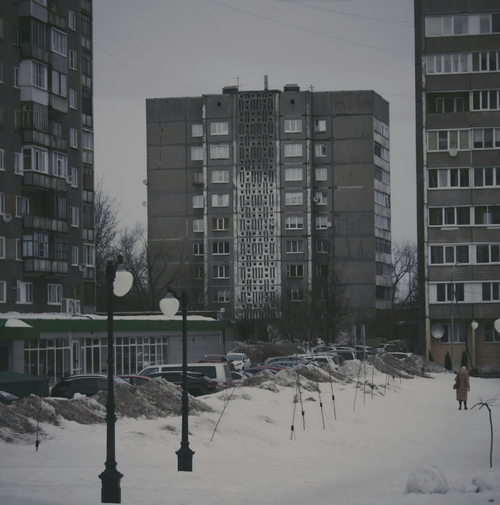 a person walking in the snow in front of tall buildings