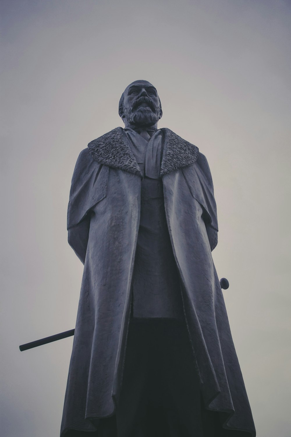 une statue d’un homme portant un manteau et tenant une épée